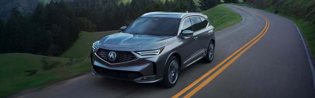 Exterior of a gray 2026 Acura MDX SUV driving down a road in Denver, CO